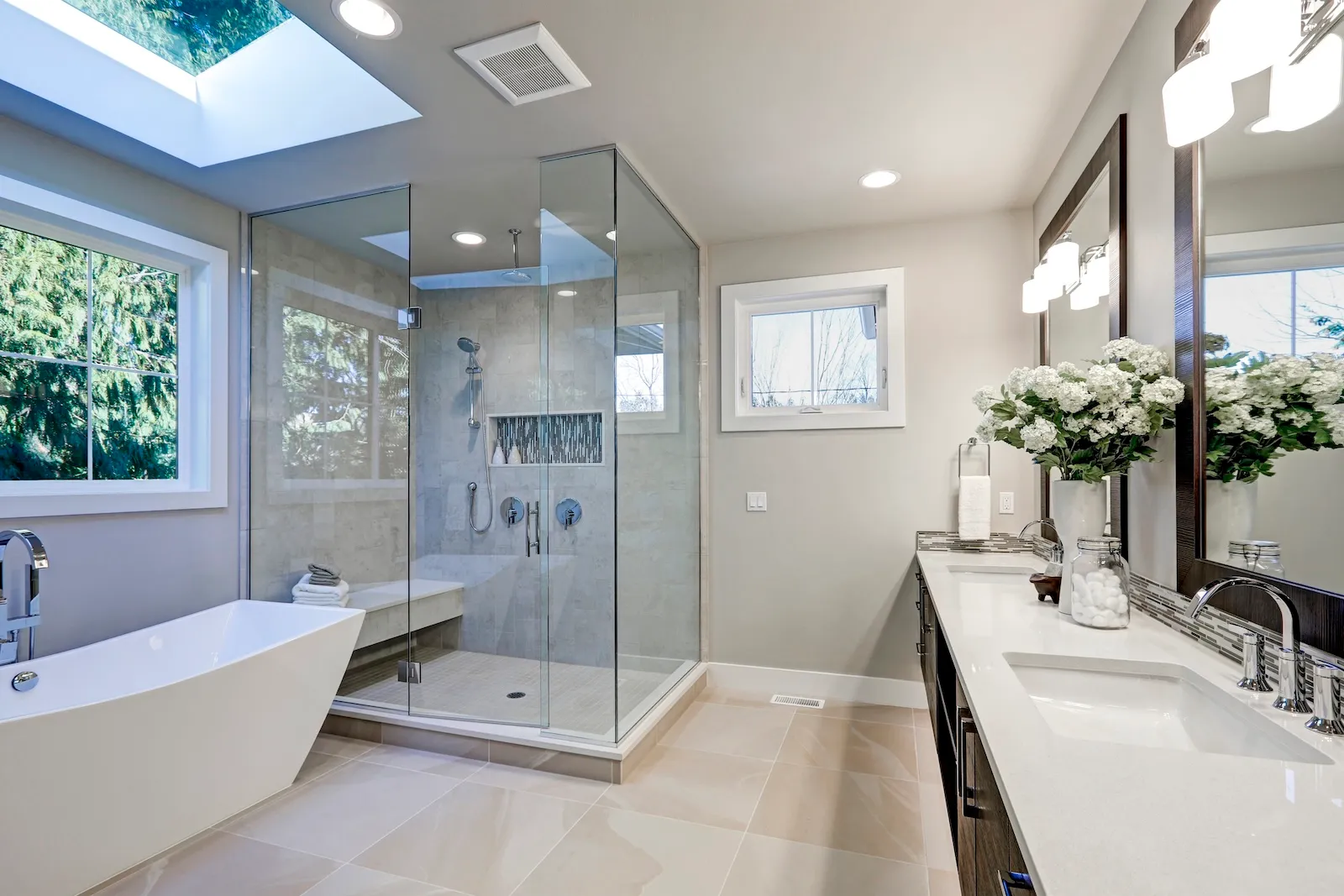Spa-inspired luxury bathroom renovation featuring skylight, glass shower enclosure, freestanding soaking tub, and dual vanities in Toronto by Leo Constra