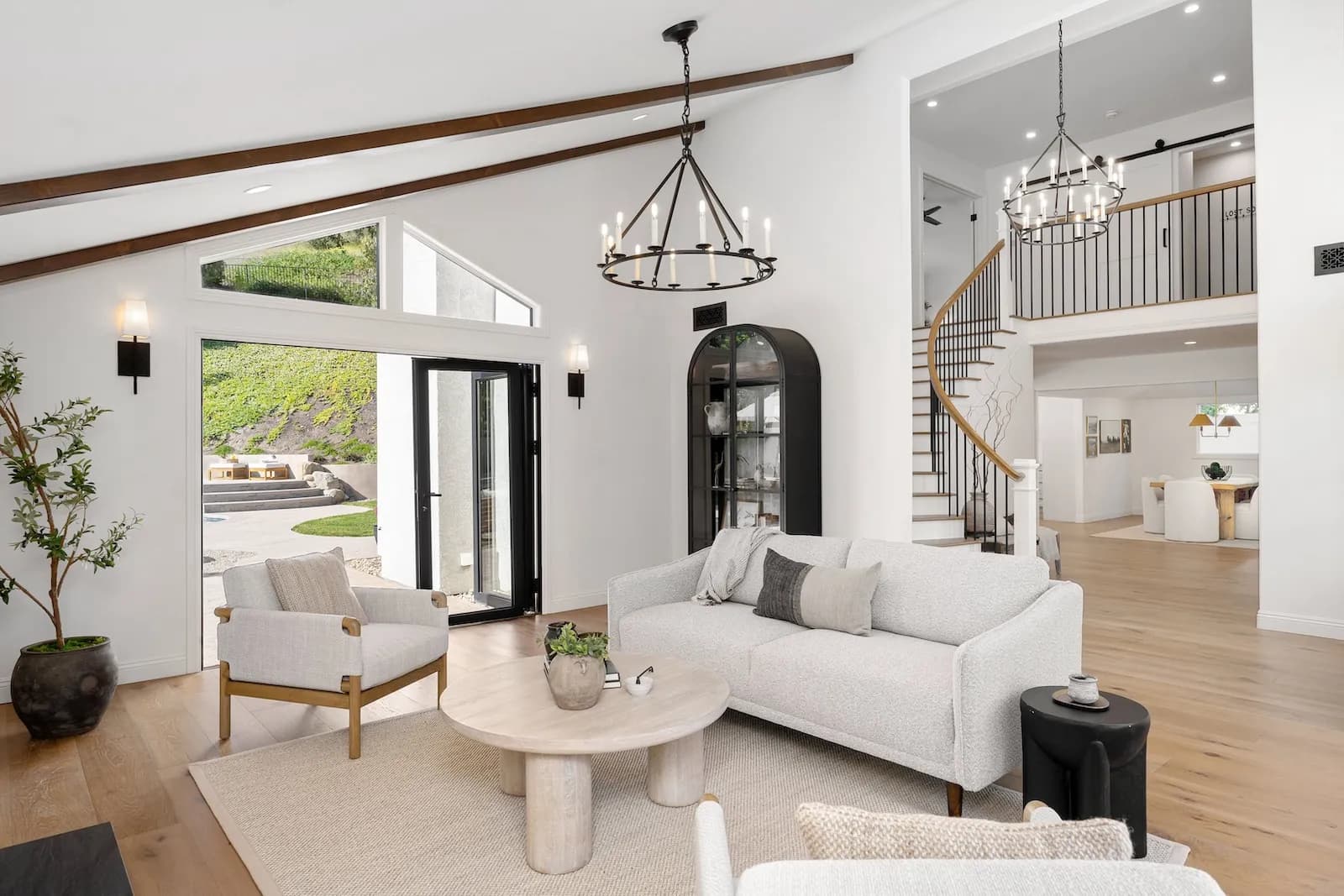 Luxury open-concept living room renovation with vaulted ceiling, exposed wood beams, black-framed french doors, and modern staircase in Toronto home by Leo Constra