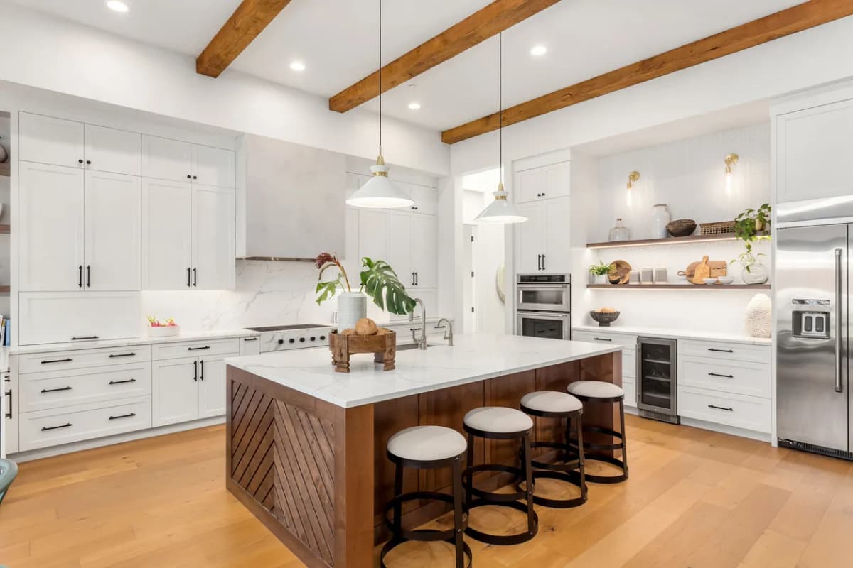 Kitchen with white cabinets, wood island, and exposed beams in Ontario